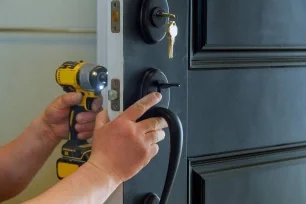 Locksmith drilling and installing a new deadbolt lock on a front door